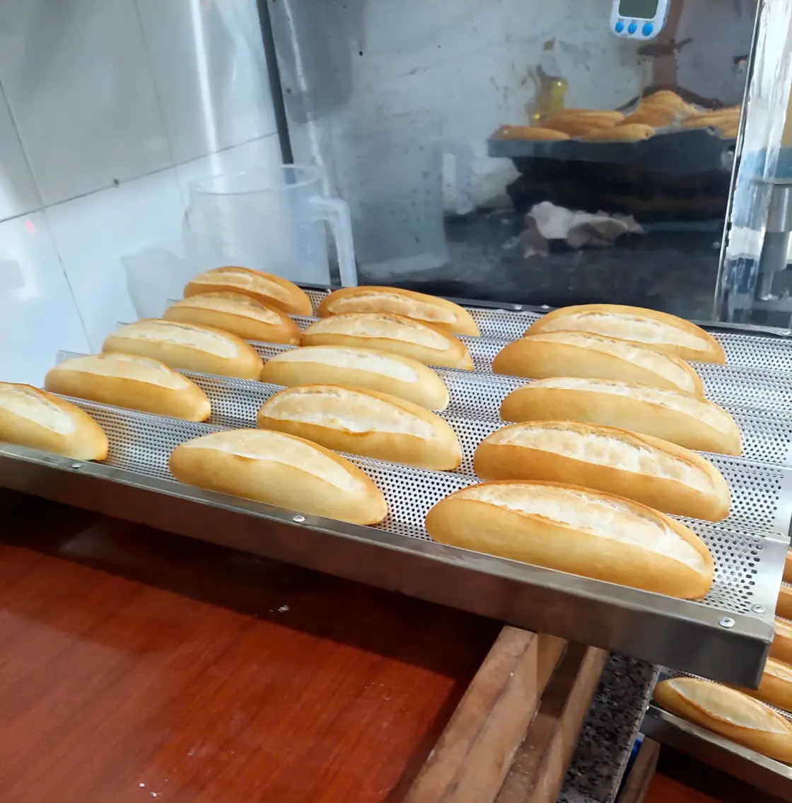 Khay 15 ổ bánh mì thành phẩm được xếp trên năm rãnh khay tại cửa hàng Đông Hòa.
